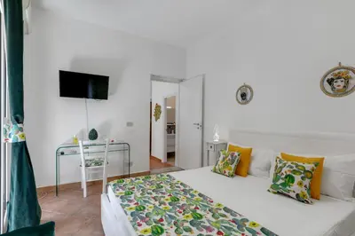 a white bedroom with a bed and a television at GuestHost - Vucciria Market Apartment with Balconies in Palermo