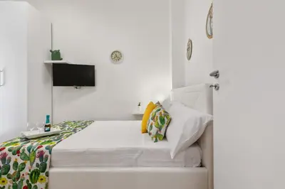 a white bedroom with a bed and a tv at GuestHost - Vucciria Market Apartment with Balconies in Palermo
