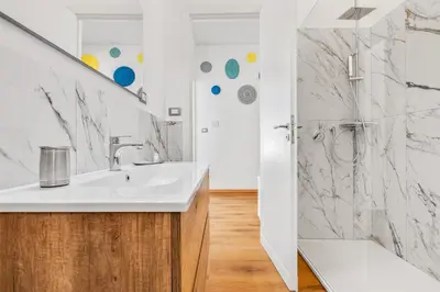 a white bathroom with a sink and a shower at GuestHost - Residenza dei Poeti - Roomy and Modern Flat in Palermo