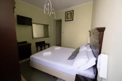 a bedroom with a bed with white sheets and a mirror at Hotel Borgo di Ciàula in Santa Flavia