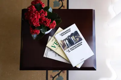 a table with a book and a vase of flowers at Hotel Borgo di Ciàula in Santa Flavia