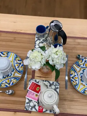 a table with plates and a tea pot and flowers at Apartament la Lumaca Kalsa in Palermo