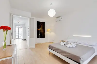 a white bedroom with a bed and a table at GuestHost - BallarHost - Ballarò Market Terrace Apartment in Palermo