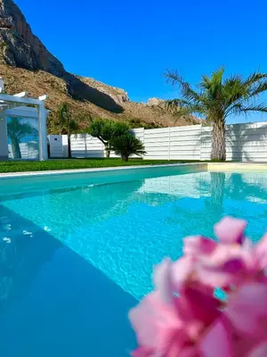 a swimming pool with blue water and a palm tree at Golden Holiday Villas Private Pools in Sicily in Terrasini