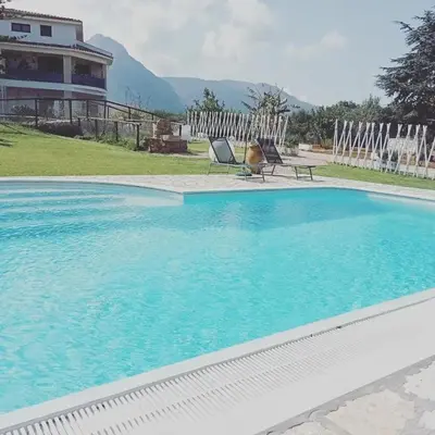 a swimming pool with two chairs and a house at Villa Michelangelo in Castellammare del Golfo