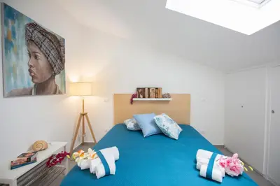 a bedroom with a blue bed with a painting on the wall at Appartamento Limone in Splendida villa Nature al mare di Scopello Zingaro in Scopello