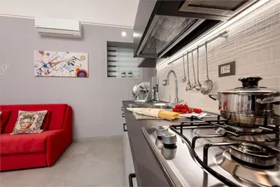 a kitchen with a stove and a red couch at Alofara Apartment in San Vito lo Capo