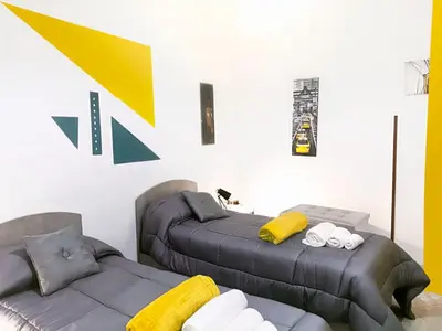 a bedroom with two beds and a yellow and white wall at Gabry central apartment Palermo in Palermo
