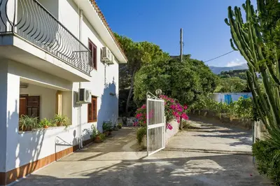 a white house with a gate and flowers at La Perla del Golfo in Castellammare del Golfo