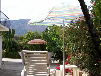 a table and chairs with an umbrella on a patio at La Perla del Golfo in Castellammare del Golfo