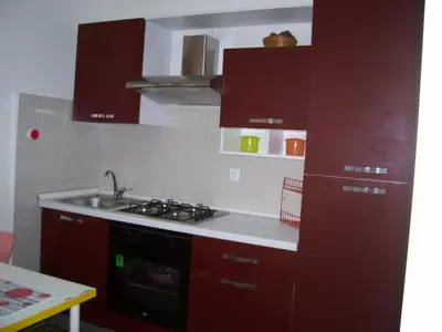 a kitchen with red cabinets and a stove and a sink at La Perla del Golfo in Castellammare del Golfo