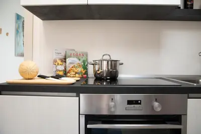 a kitchen with a stove with a pot and a cutting board at Appartamenti in Villa Nature con vista mare e monti in Scopello