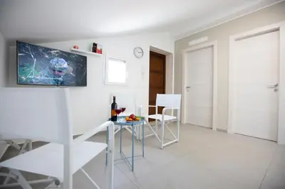 a white living room with a table and chairs at Appartamenti in Villa Nature con vista mare e monti in Scopello