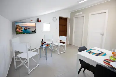 a white living room with a table and chairs at Appartamenti in Villa Nature con vista mare e monti in Scopello