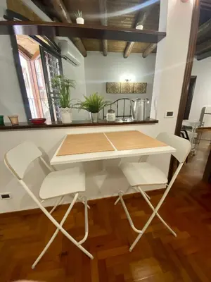 a table with white chairs in a room at Cathedral Sweet home in Palermo