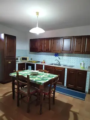 a kitchen with a table and wooden cabinets at Casa vacanze BY THE SEA in Trabia