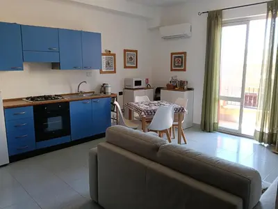a living room with a couch and a kitchen with a table at Salina in Trappeto