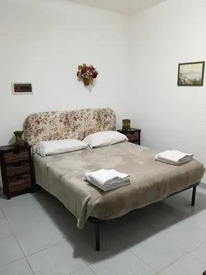 a bed with a floral headboard and two towels on it at Salina in Trappeto