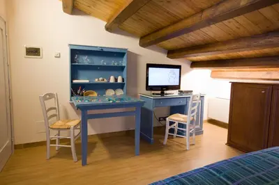 a bedroom with a blue desk with a computer and chairs at Sicilia Ovest - Sea View Balcony Cerri in Castellammare del Golfo