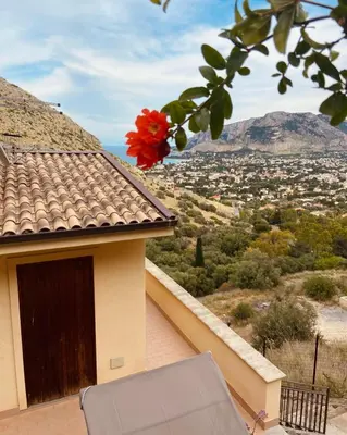a house with a balcony with a red flower at L'Oasi dell'Eremita in Mondello