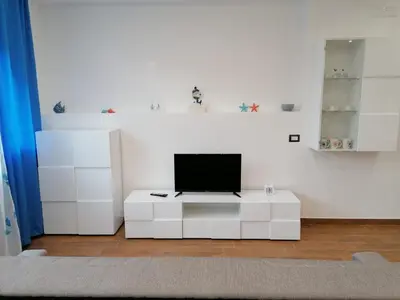 a white living room with a flat screen tv on a table at Momaliar House in Campofelice di Roccella