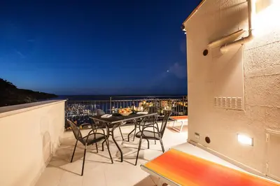 a balcony with a table and chairs and the ocean at Sicilia Ovest - Terrazza Orologio e Terrazza Sul Mare in Castellammare del Golfo