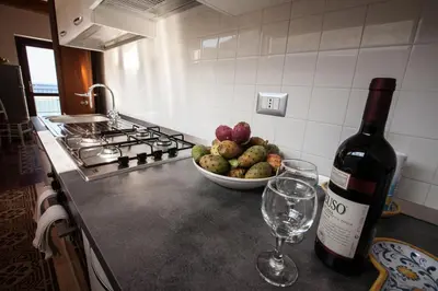 a bottle of wine and a bowl of fruit on a kitchen counter at Sicilia Ovest - Terrazza Orologio e Terrazza Sul Mare in Castellammare del Golfo