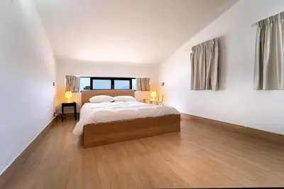 a bedroom with a large bed with white walls and wooden floors at Kòre rooms in Castellammare del Golfo