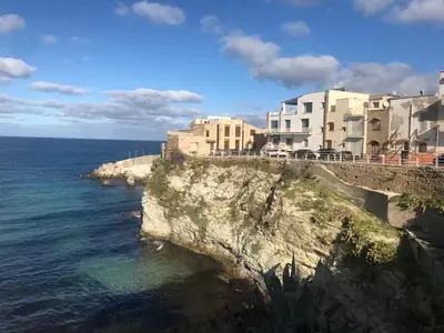 a building on top of a cliff next to the ocean at By the Sea Apartment #4 in Terrasini