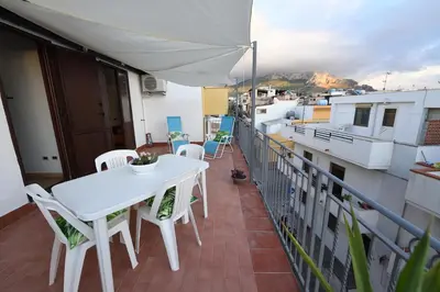a balcony with a table and chairs and an umbrella at By the Sea Apartment #4 in Terrasini