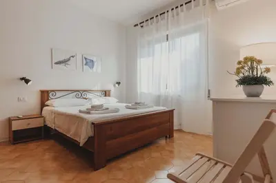 a bedroom with a bed and a chair and a window at Villa Levante, relax esclusivo a due passi dal mare vicino Cefalù in Lascari