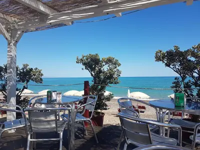 a table and chairs on a beach with the ocean at Villa Levante, relax esclusivo a due passi dal mare vicino Cefalù in Lascari
