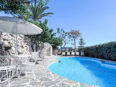 a swimming pool with chairs and an umbrella at Apartment Bouganville di Patrizia by Interhome in Castellammare del Golfo