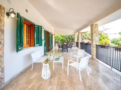 a patio with white chairs and a table on a balcony at Villa La Vela by Interhome in Scopello