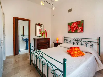 a bedroom with a bed with an orange pillow on it at Villa La Vela by Interhome in Scopello