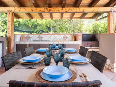 a wooden table with chairs and blue plates on it at Villa Nicole con Dependance by Interhome in Castellammare del Golfo