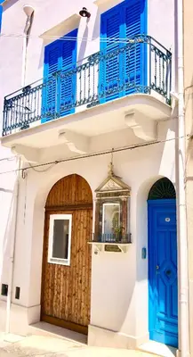 a building with blue doors and a balcony at Casa Colore Loft in Castellammare del Golfo