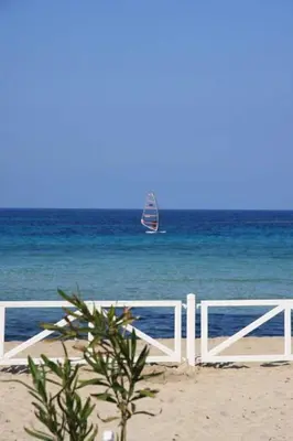 a white fence on the beach with a kite in the ocean at mondello lilla' room in Palermo