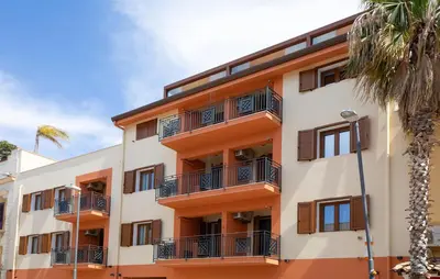 an orange and white building with balconies and a palm tree at Beautiful Apartment In Balestrate in Balestrate