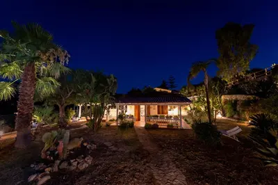 a house with palm trees in front of it at night at NUOVA Villa Intera Guidaloca in Scopello