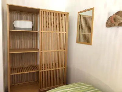 a wooden book shelf next to a wall with a mirror at TORRE MARIZA Guidaloca in Scopello