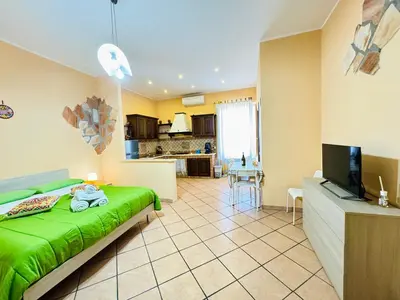 a bedroom with a green bed and a kitchen at Le Maioliche in Sferracavallo