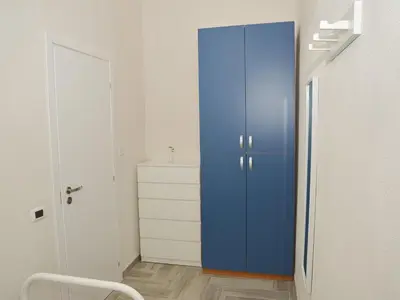 a blue cabinet in a white room with a chair at I TRAMONTI D'ASPRA in Bagheria