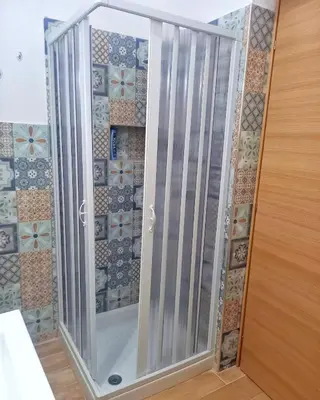 a glass shower door in a room with tiles at Le notti di Nettuno a Isola Delle Femmine in Isola delle Femmine