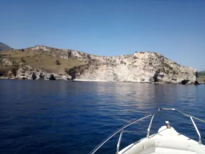 a boat on a body of water with a mountain at Residenza sabbia dorata in Alcamo