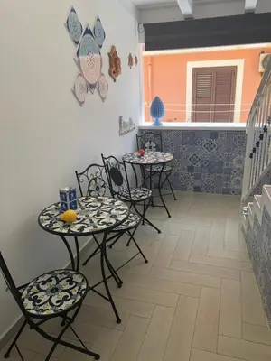 a patio with four tables and chairs and a balcony at MARINA BAY in Terrasini