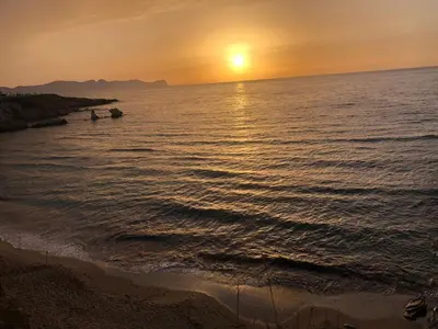 a sunset over the ocean with two boats in the water at MARINA BAY in Terrasini