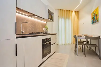 a kitchen with a sink and a stove and a table at Porta del Golfo Apartments & Suites in Castellammare del Golfo