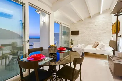 a dining room and living room with a table and chairs at Porta del Golfo Apartments & Suites in Castellammare del Golfo