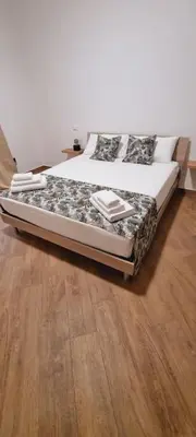 a bed sitting on a wooden floor in a bedroom at Christian Guest House in Terrasini